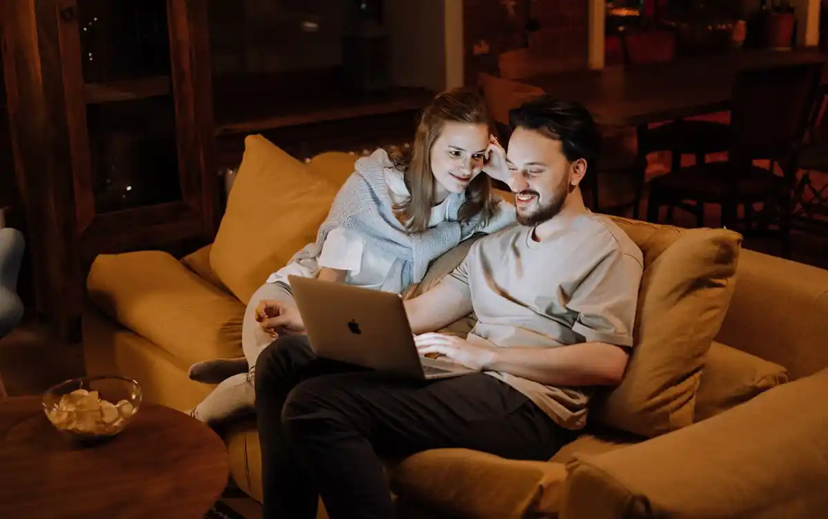 A couple relaxing on the sofa with a laptop during a cozy evening at home.
